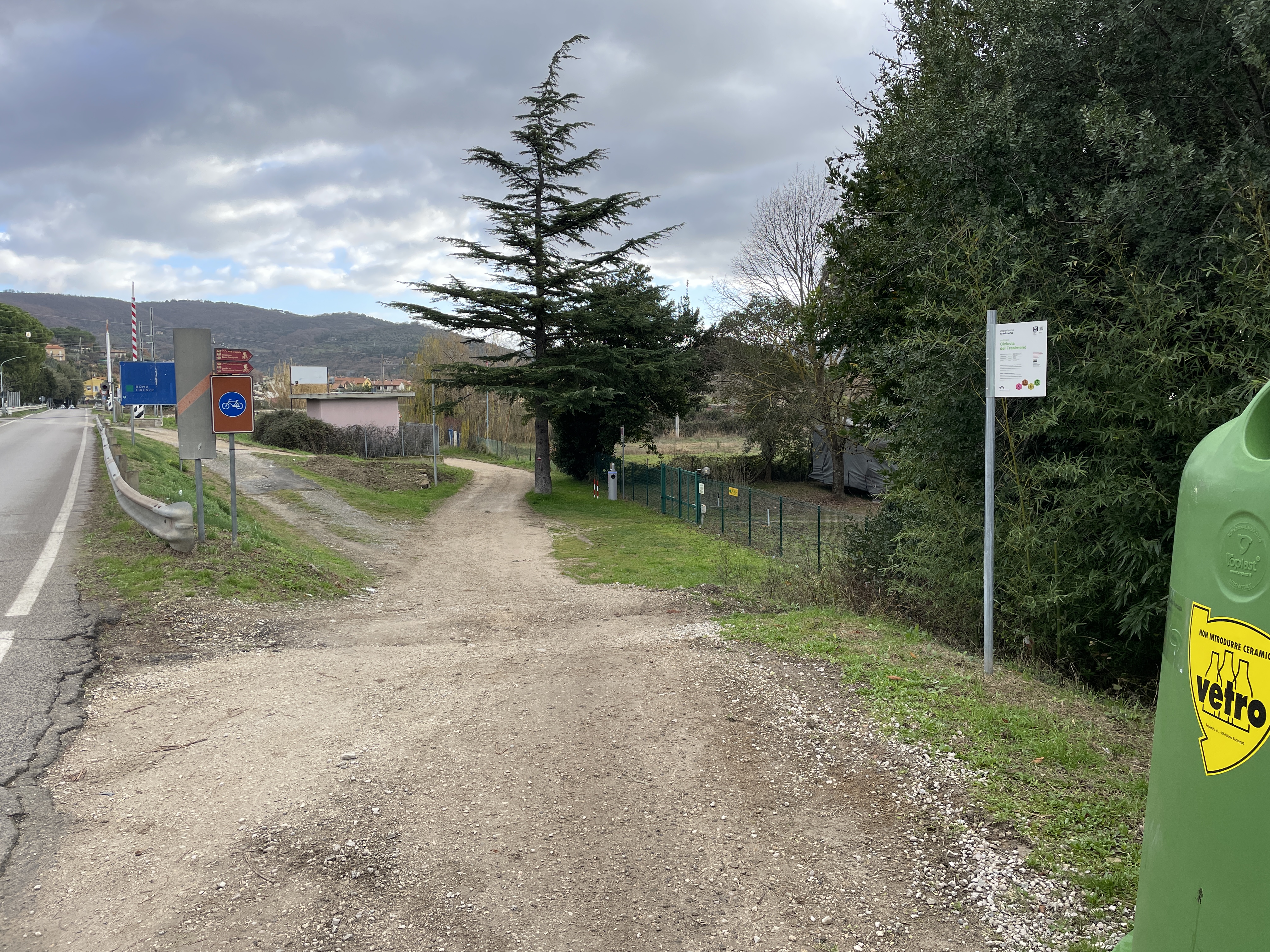 Geschotterter Abschnitt des ausgeschilderten Rad- und Fußgängerwegs. Er zweigt rechts von der Regionalstraße ab und führt bergab, mit einer anfänglichen Verkeilung.